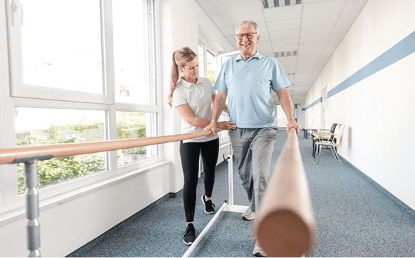 Elderly man walking with physiotherapist support