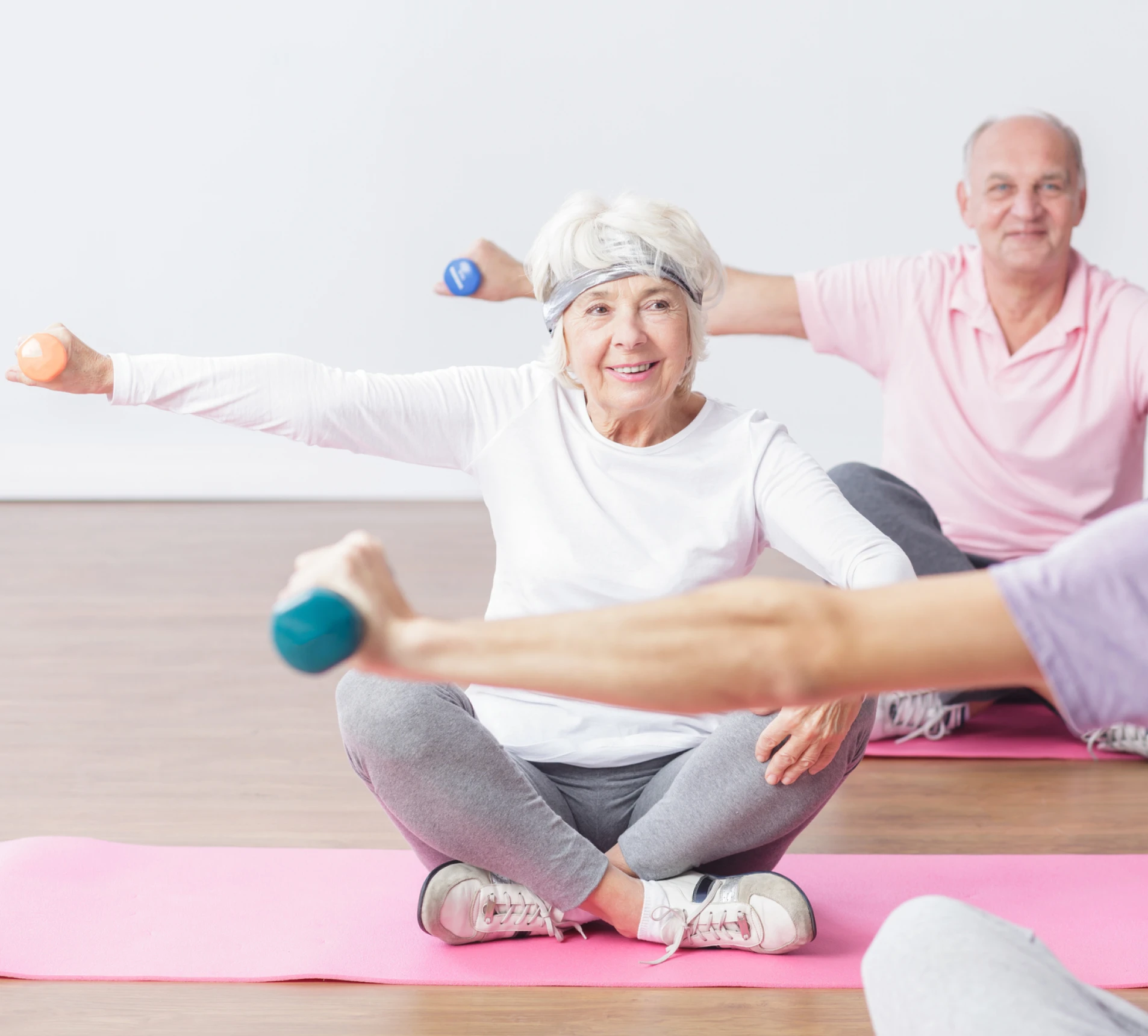 Seniors exercising with dumbbells on yoga mats