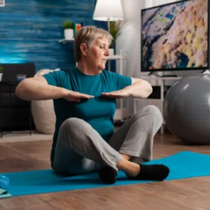 Older woman exercising on a yoga mat in a cozy living room.