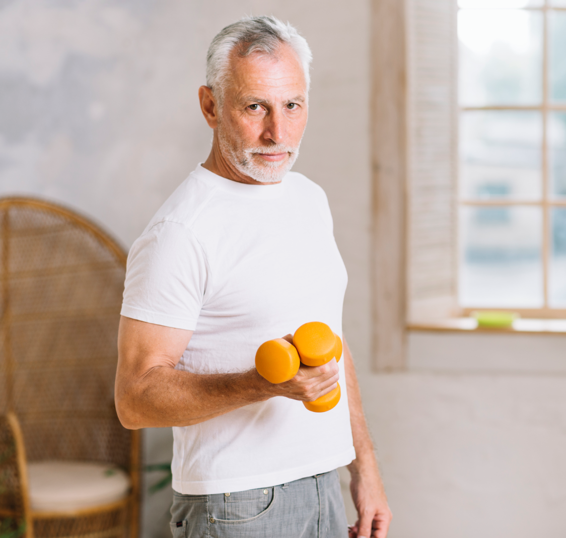 Mature man lifting oranges like dumbbells in a bright room.