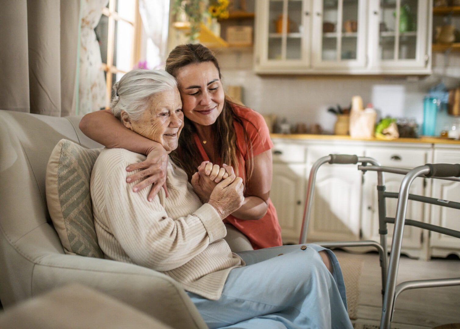 A young woman lovingly embraces an elderly woman at home.