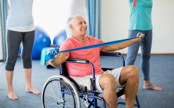 Elderly man in wheelchair exercising with resistance band.