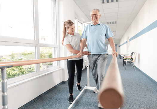 Elderly man walking with physiotherapist support