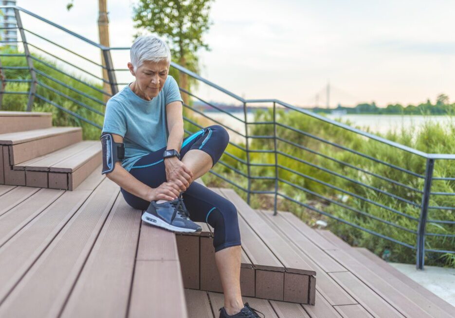 Older woman adjusting sneakers outdoors