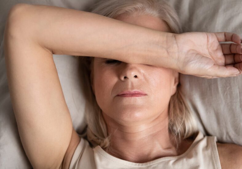 Woman shielding eyes while resting in bed