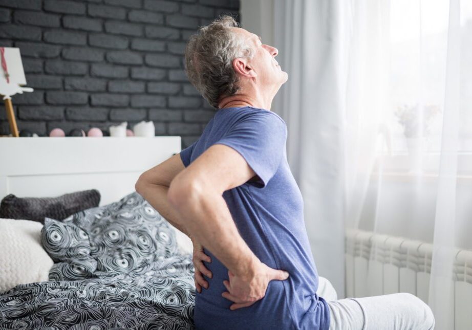 Man with back pain sitting on bed